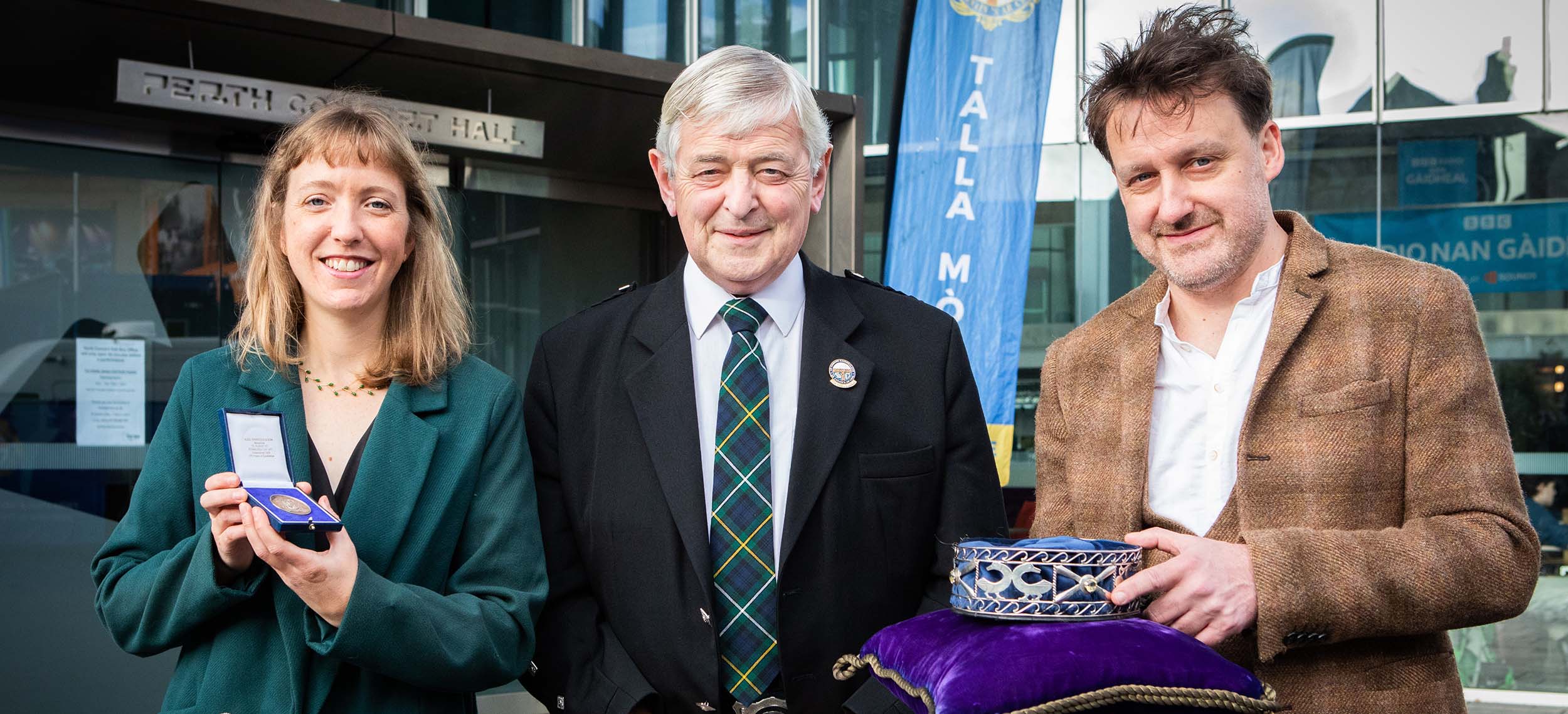 Sheena Amos agus Pàdraig MacAoidh còmhla ri Ailean Caimbeul, Ceann-suidhe a’ Chomuinn Ghàidhealaich. Sheena Amos agus Pàdraig MacAoidh còmhla ri Ailean Caimbeul, Ceann-suidhe a’ Chomuinn Ghàidhealaich.